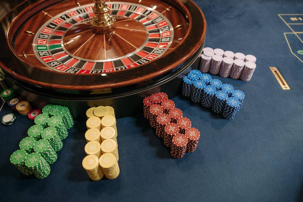 Chip kasino dan roda roulette di meja permainan