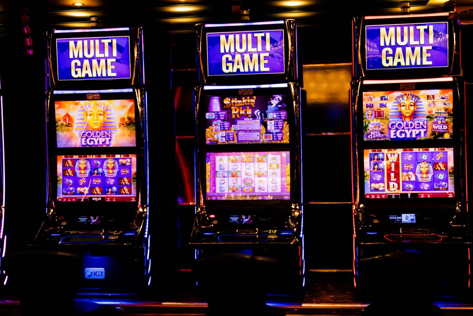 Deretan mesin slot dengan lampu neon di ruang kasino